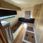 Photo de la cabine babord du bateau avec le même parquet au sol. On y voit deux sommiers pour des lits simples.