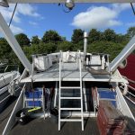 Photo du poste de pilotage extérieur accessible via une petite échelle blanche. Le poste de pilotage est également de couleur blanche et se situe sur la grande terrasse en bois gris.
