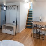Image de la chambre d'hôte avec deux lits simples, un endroit pour ranger ses vêtements, une petite table à manger en bois ainsi qu'une cuisine.