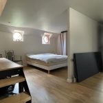 Image de la chambre parentale avec un lit double au fond à droite et un petit escalier au premier plan.