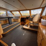 Image du poste de pilotage du bateau. Il se situe en face de la table à manger. Ce dernier est installé sur un meuble en bois.