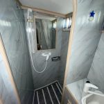 Photo de la douche en marbre. Un miroir est installé à l'intérieur de la douche.