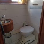 Photo de la seconde salle de bain du bateau. Elle est blanche. On voit sur la photo le toilette surélevé et le lavabo en bois.