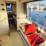 Vedette fluviale Jeanneau Eau Claire 930 Cassis (1985) – salon avec siège pilote rouge et cuisine