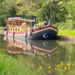 Péniche Hagenaar 18 m ANNA (1911) – vue extérieure sur un canal bordé d'arbres