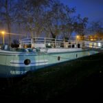Péniche Freycinet 30 m Au Fil de l'Eau (1956) – étrave bâbord de nuit à quai, éclairage