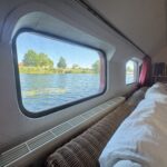 Péniche Luxe-Motor Dulcinea (1929) – vue sur la rivière depuis le canapé du salon à travers une grande fenêtre