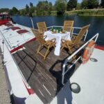 Péniche Luxe-Motor Dulcinea (1929) – terrasse en bois sur le pont avec table dressée et chaises