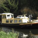 Péniche Luxe-Motor 14,50 m (1928) – en navigation sur un canal bordé d'arbres