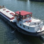 Péniche Luxe-Motor Dulcinea (1929) – vue aérienne trois-quarts arrière en navigation, timonerie au taud rouge