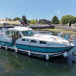 Vedette fluviale Nicols 1100 Lodève (1998) – vue trois-quarts avant sur le canal, quai au fond