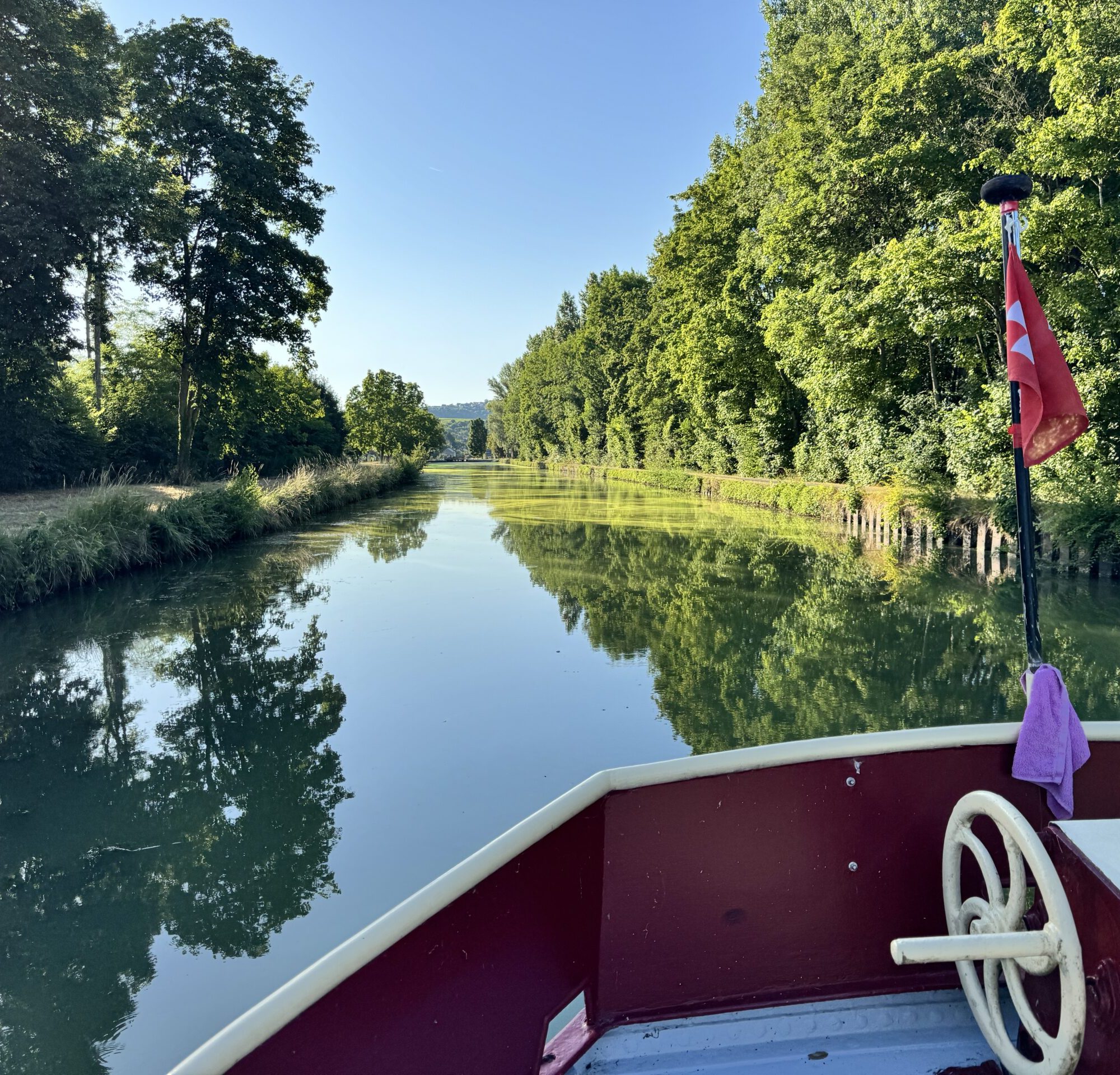 Image de l'avant d'un bateau avec vue sur les canaux de France. Verdure et ciel bleu