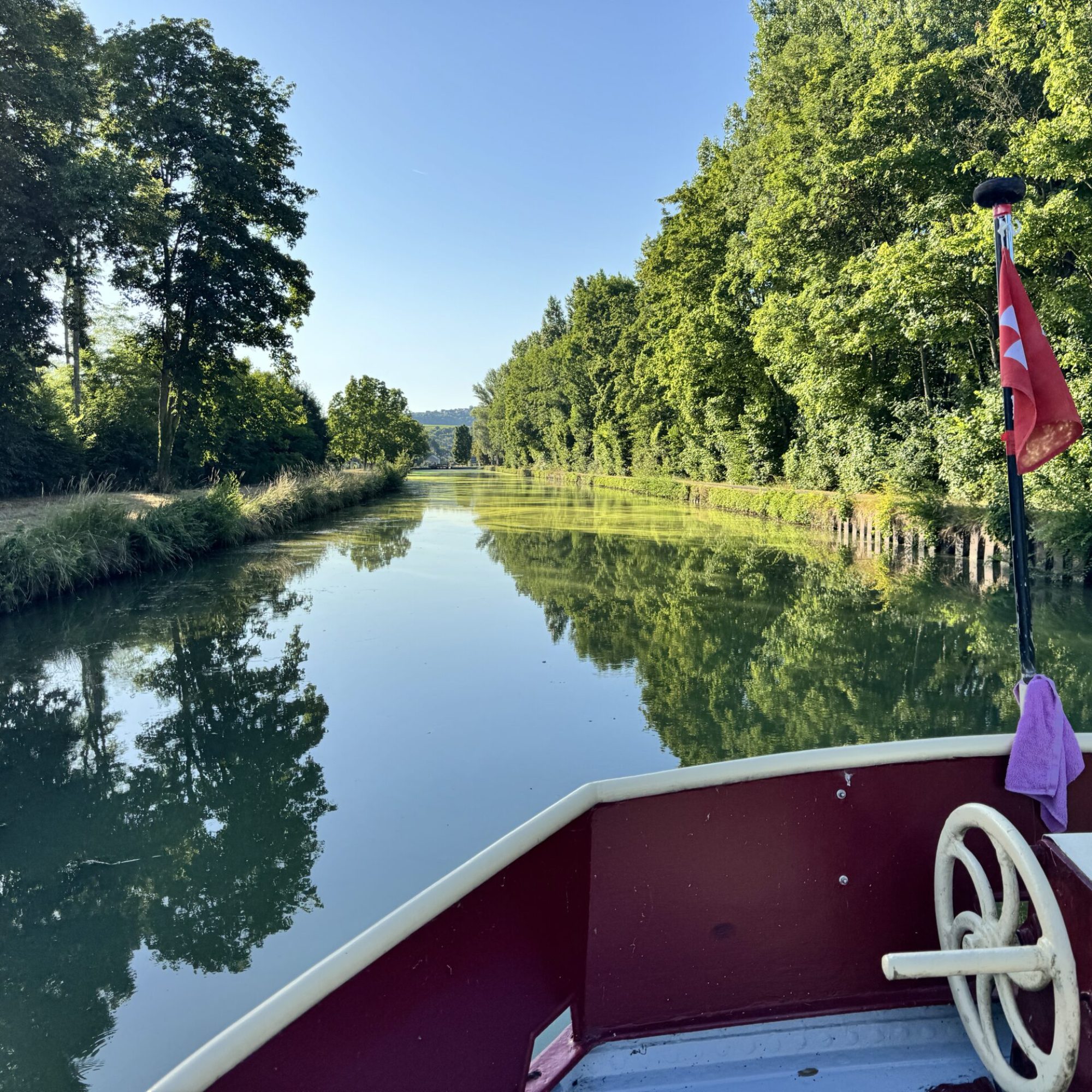 Image de l'avant d'un bateau avec vue sur les canaux de France. Verdure et ciel bleu